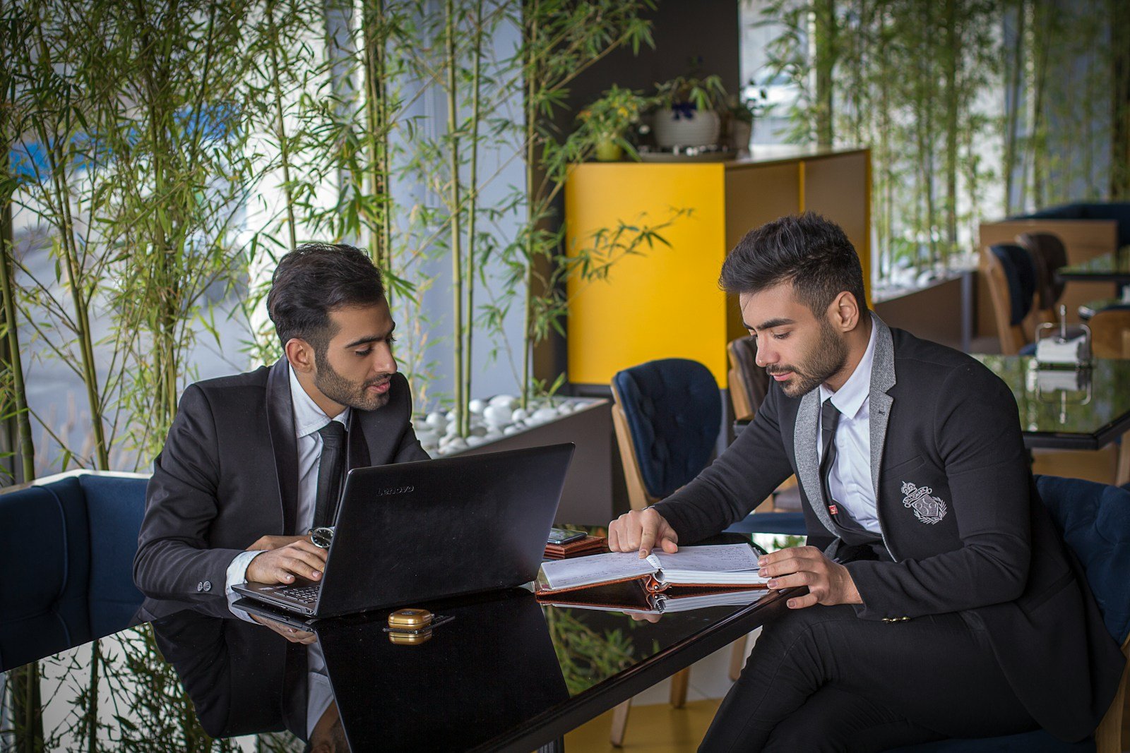 man in black suit jacket sitting beside man in black suit